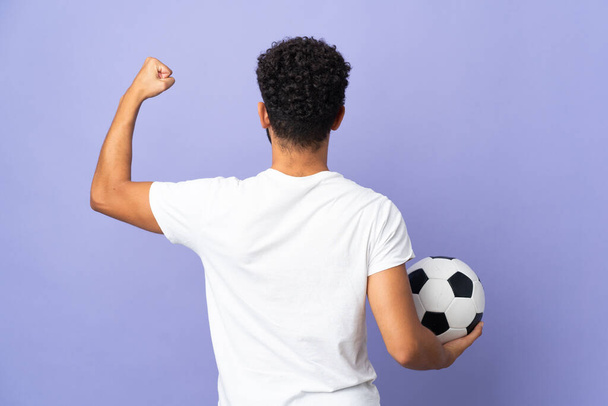Молодий марокканець ізольований на фіолетовому тлі з футбольним м "ячем. - Фото, зображення