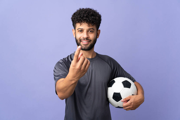 Guapo marroquí joven futbolista hombre sobre aislado en púrpura fondo haciendo gesto que viene - Foto, imagen