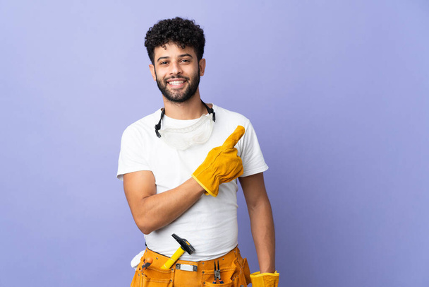 Young electrician Moroccan man isolated on purple background pointing to the side to present a product - Foto, Bild