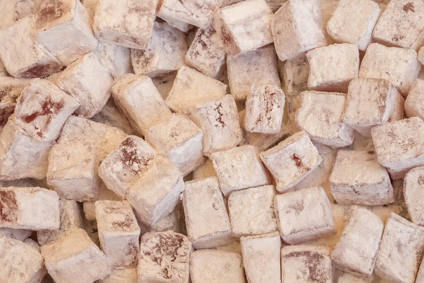 A wholesale box of rosewater-flavored Turkish delight sweet cubes dusted with icing sugar. - Fotó, kép