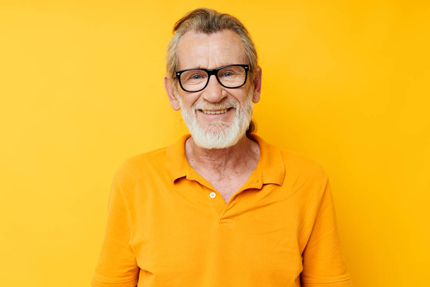Portrait of happy senior man wearing glasses yellow shirt posing unaltered - Фото, изображение