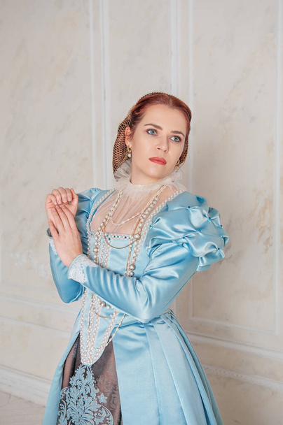 美しいです若い女性で中世のスタイルの青いドレススタンドで部屋 - 写真・画像