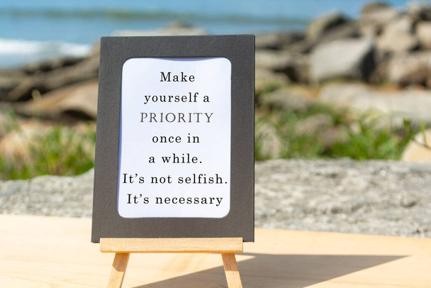 Motivational and Inspirational quote on a notepad with blurred beach background. Make yourself a priority once in a while. It is not selfish. It is necessary - Foto, Bild