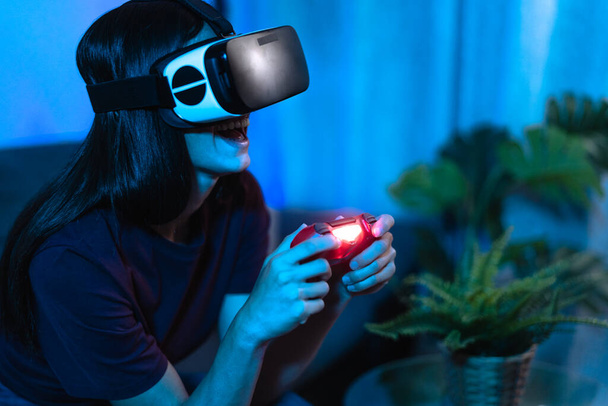Young woman playing with virtual reality glasses at home - Tech and metaverse concept - Foto, afbeelding