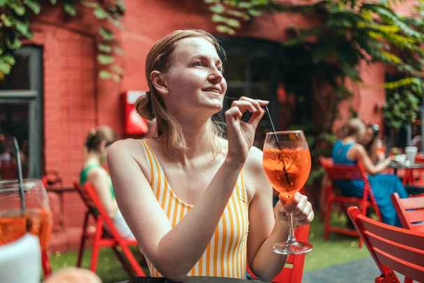Onnellinen nainen juo klassista italialaista aperitiivi aperoli spritz cocktailia. Perinteinen kesä tuore juoma - Valokuva, kuva