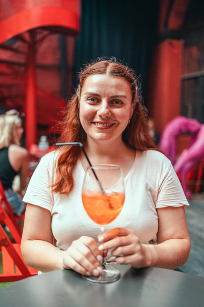 30 років жінка відпочиває і насолоджується келихом вина холодного коктейлю Aperol spritz на фоні ресторану
. - Фото, зображення