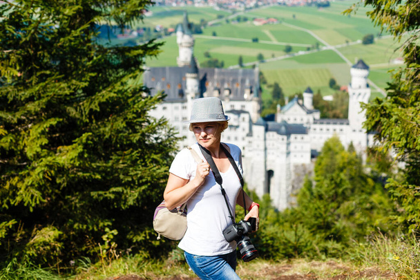 Jonge vrouw met beroemd koninklijk kasteel Neuschwanstein op achtergrond. Gelukkig winterweekend op het platteland. Vakantie in de bergen. Alpen, Beieren, Duitsland - Foto, afbeelding