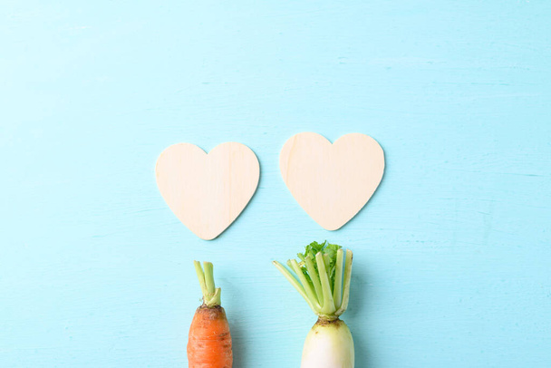 Органічна морква і біла редиска з формою серця на світло-синьому фоні, концепція любові, день святого Валентина. - Фото, зображення