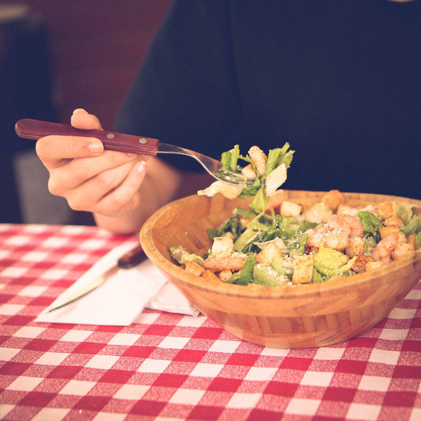 Portrait of attractive caucasian smiling woman eating salad, focus on hand and fork. - Foto, Imagem