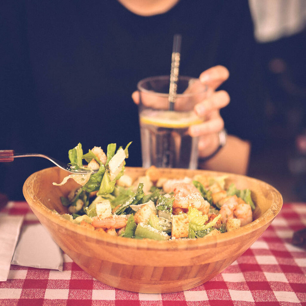 Portrait of attractive caucasian smiling woman eating salad, focus on hand and fork. - Foto, Bild