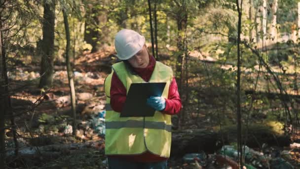 Женщина-эколог в рабочей одежде штрафует за сброс пластиковых отходов в парке - Кадры, видео