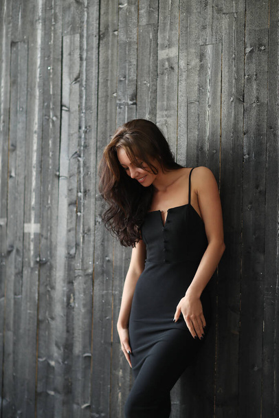 Жінка в чорній сукні на дерев'яному фоні стіни
 - Фото, зображення