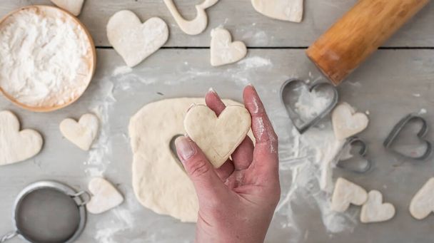 Heart cut from dough in the hand. Cooking gingerbread cookies for the holidays: christmas, new year, st. valentine's day, advent. Family bakery. Step by step recipe.  - Photo, Image
