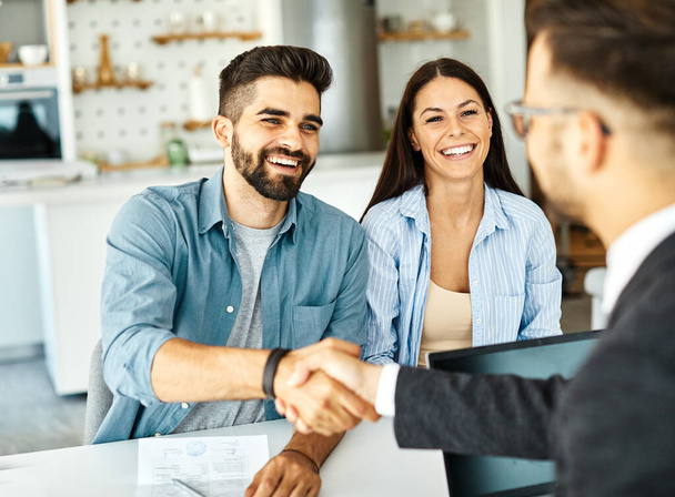 young couple shaking hands deal contract real estate investment business agreement agent handshake signing - Photo, Image