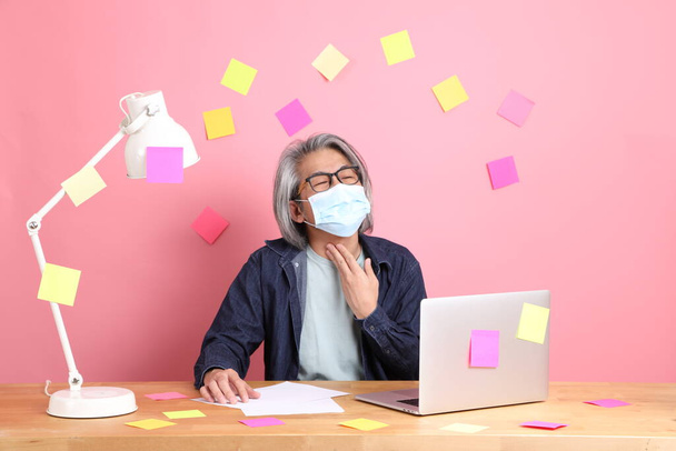 The senior Asian man sitting at working desk with a lot of paper work against the pink background. - Фото, зображення