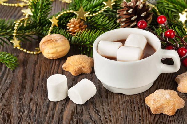 Hot chocolate or cocoa drink with marshmallow in a white cup, sweet homemade cookies and decorations on a brown wooden background. Christmas and new year traditional food.  - Fotografie, Obrázek