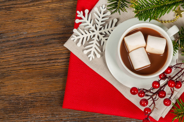 Hot chocolate or cocoa drink in a white cup and golden decorations on a brown wooden background. Christmas and new year traditional food. Top view - Foto, afbeelding