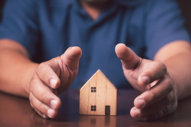 Zakenman Hand holding hout huis model, Planning kopen Onroerend goed, Planning om onroerend goed te kopen investering en hypotheek financieel concept. - Foto, afbeelding