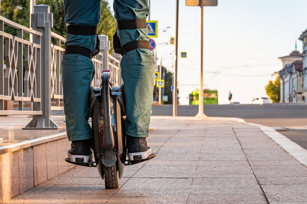Rider's legs in protective gear on an electric unicycle (EUC). Driving around the city on an electric monowheel. - 写真・画像