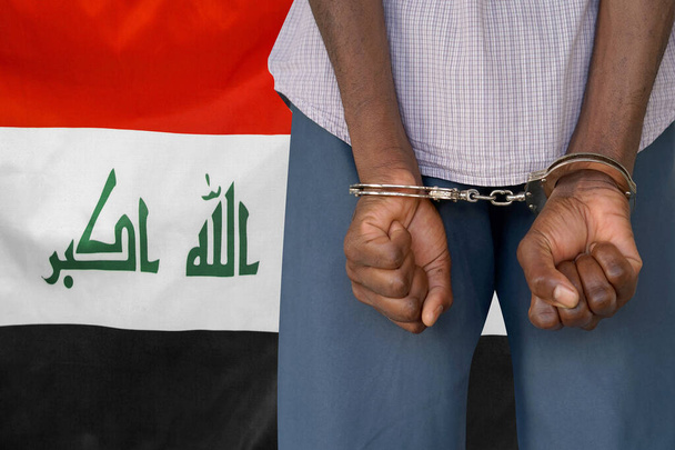 Afrikkalainen mies, jolla on käsiraudat Irakin lipun alla. Taustakuva. Käsitys vankiloista ja korruptiosta Irakissa - Valokuva, kuva