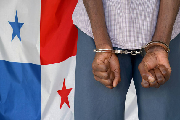 Африканец с наручниками на фоне флага Панамы. Вид сзади. Концепция тюрем и коррупции в Панаме - Фото, изображение
