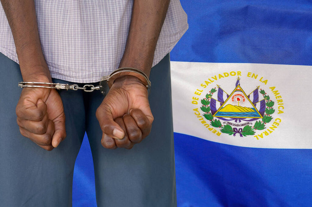 Αφρικανός με χειροπέδες στο φόντο της σημαίας του Ελ Σαλβαδόρ. Πίσω όψη. Έννοια των φυλακών και της διαφθοράς στο Ελ Σαλβαδόρ - Φωτογραφία, εικόνα