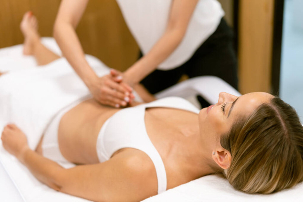 Жінка середнього віку має масаж живота в салоні краси
. - Фото, зображення