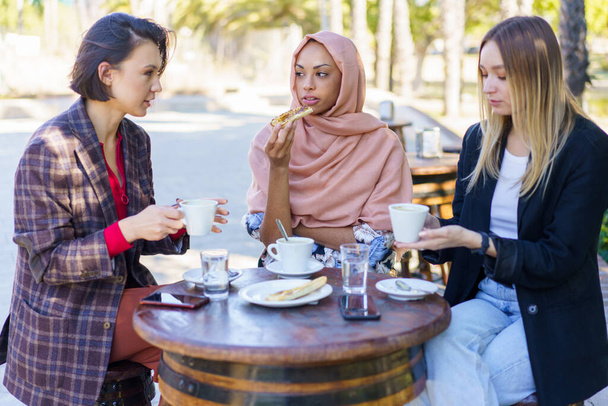Nuoret monipuoliset naiset juovat kahvia katukahvilassa - Valokuva, kuva