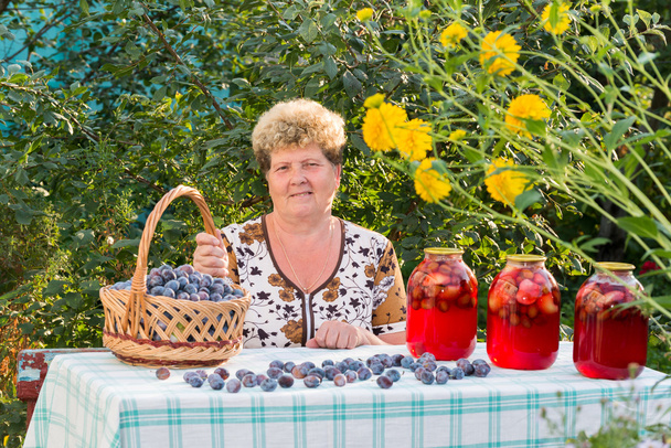 elderly woman with a jar of plum compote - Zdjęcie, obraz