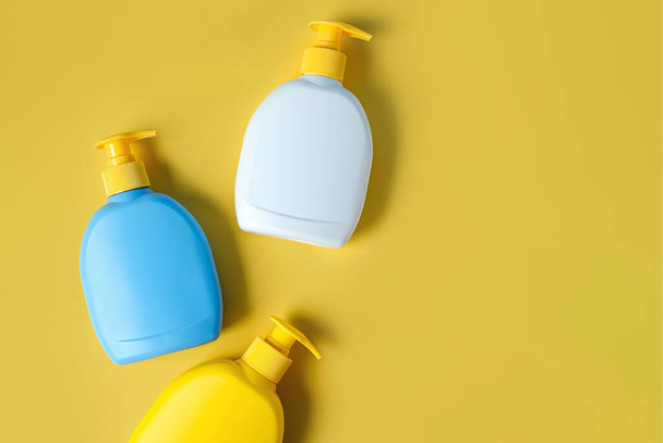 Мыло или шампунь бутылки на желтом фоне. Дизайн упаковки пустых бутылок. - Фото, изображение