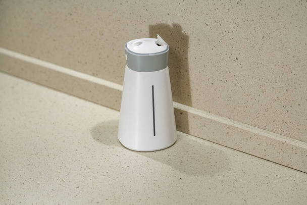 Compact wireless room humidifier made of white and gray plastic against a stone wall - Photo, Image