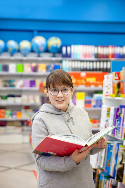Portrait of   eleven - year - old teenage girl in   bookstore .  - Φωτογραφία, εικόνα