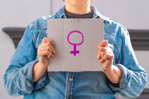 Frau mit Pappschild mit weiblichem Symbol. Feministisches Konzept, Feminismus, feministische Aktivistin - Foto, Bild