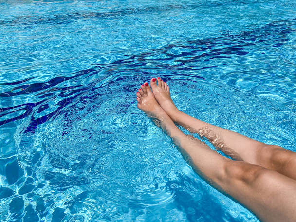Woman rubbing her foot at the poolside. - Photo, Image