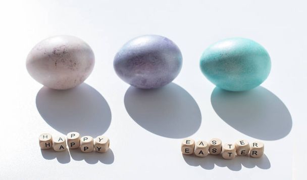 Paskalya konsepti. Beyaz arka planda pembe, mor ve mavi yumurtalar. Minimalizm. Sert gölgeler - Fotoğraf, Görsel