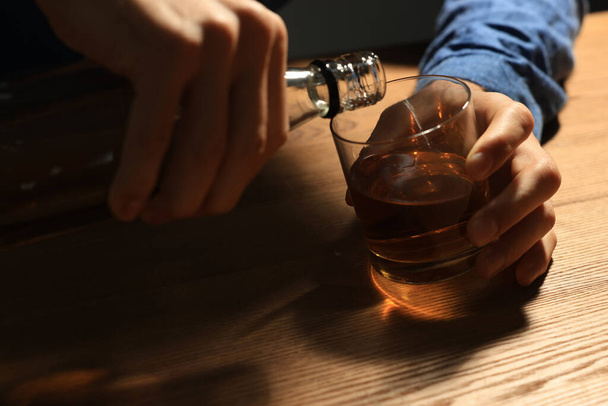 Addicted man with alcoholic drink at wooden table, closeup - Foto, Imagem