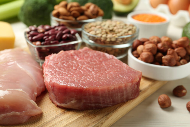 Fresh meat and other products on white wooden table, closeup. Sources of essential amino acids - Fotografie, Obrázek