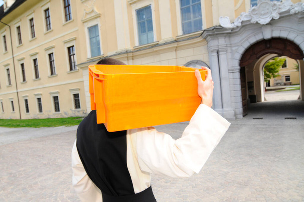 цистерціанський батько ходить з помаранчевою поштовою скринькою на плечі
 - Фото, зображення