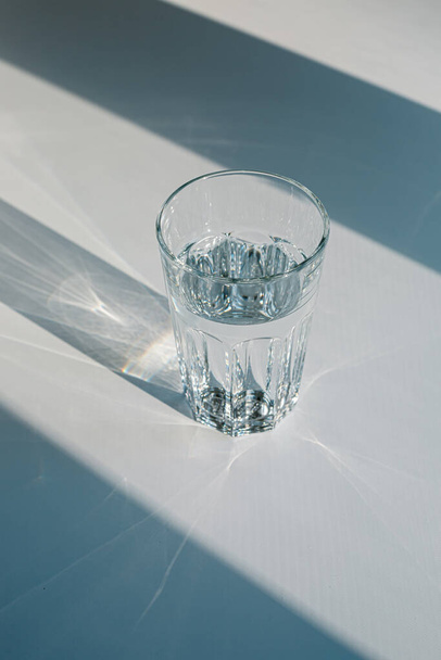 Склянка мінеральної фільтрованої води та сонячного світла на білому тлі, включаючи відсічний контур
.  - Фото, зображення
