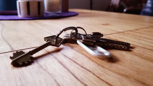 Una donna che prende le chiavi dal tavolo di legno a casa. Primo piano. Zoom In.  - Filmati, video