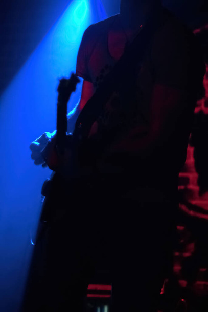 クラブでのロックコンサート。青い照明だ。ギタリストのシルエット - 写真・画像