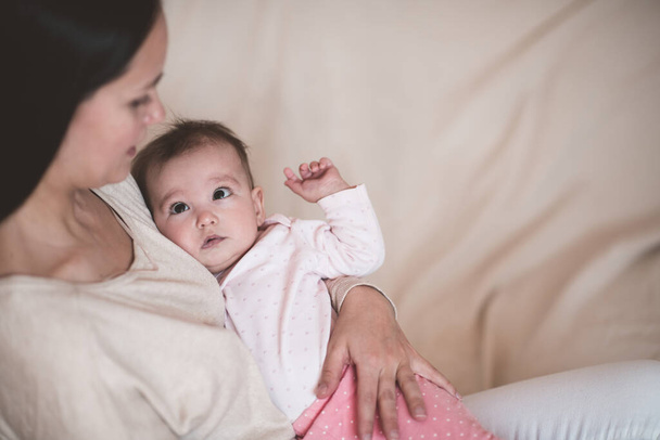 赤ん坊を抱えている女性は、母の手の上に寝そべってパジャマを着る。おはようございます - 写真・画像