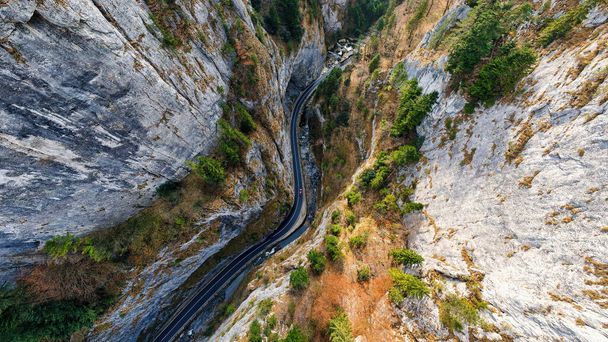 ルーマニアの自然の空中ドローンビュー。カルパチア山脈、岩場の丘や崖、道路や渓谷の水の流れ - 写真・画像