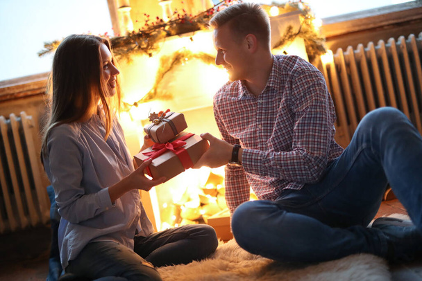 Beautiful couple by the fireplace during the evening - Photo, Image