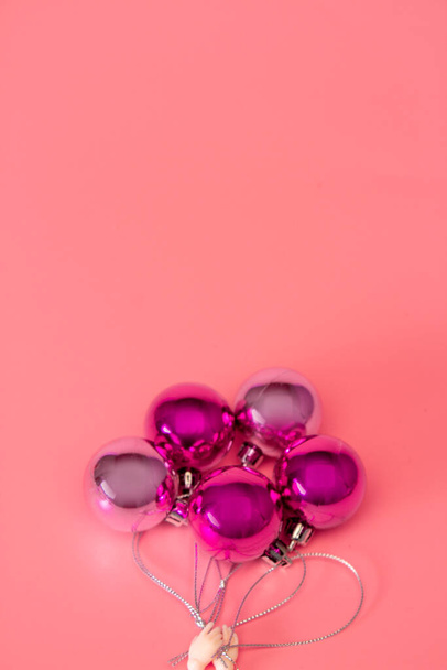 Muñeca de mano sosteniendo bolas de Navidad rosa en forma de globos de helio concepto creativo mínimo - Foto, Imagen
