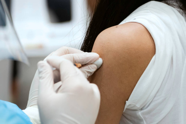 アジアの医者は女性にオミクロンcovidウイルスワクチンブースターの投与量を与え. - 写真・画像