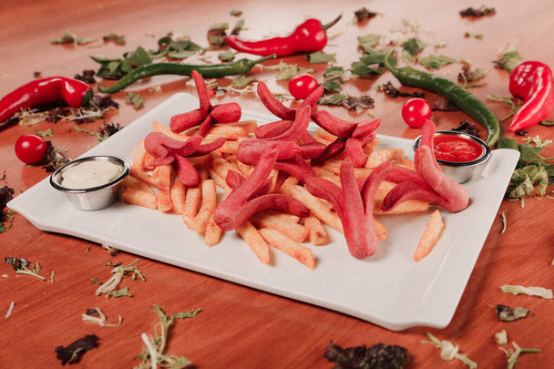 Вкусные закуски, картофель фри, луковые кольца, весенние рулеты или сосиски на столе  - Фото, изображение