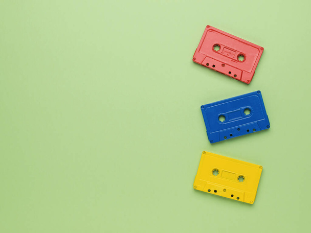 Drie veelkleurige cassettes op een lichtgroene achtergrond. Vintage stijl in geluidsopname. Vlakke plaat. - Foto, afbeelding