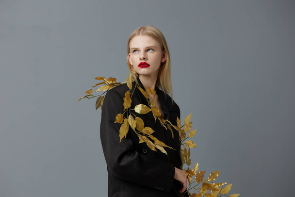 グラマラスな女性の装飾黒ジャケット黄金の葉隔離された背景 - 写真・画像