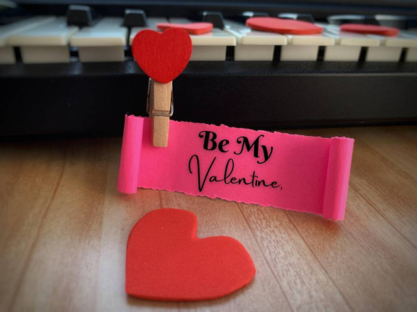 Be my Valentine text on torn paper with keyboard, brown table and heart shape background. Valentines Day concept. - 写真・画像